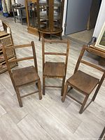 Set of 3 antique style brown wooden children's chairs with ladder back design, solid wood seats, and straight legs shown from front angle.