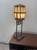 Side view of Tiffany style stained glass lamp lit, showing multicolor glass and metal frame detail on wooden surface