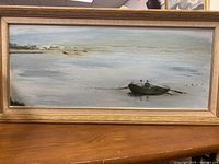 Front view of framed oil on canvas painting showing a landscape with a boat and distant sailboats on the water.