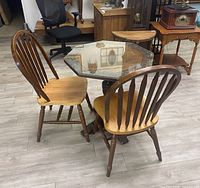 Photo of hexagonal wooden table with clear glass top and two matching wooden chairs, showing the shape and design of the set.