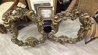 Wide view of both ornate frames leaning side by side