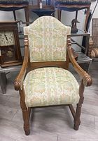Front view of vintage wooden armchair with floral upholstery showing backrest and seat.