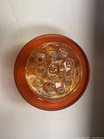 Top view of the red glass vintage flower bowl showing the clear glass frog insert with multiple holes inside the bowl.