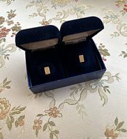 Two small gold bars inside a blue velvet jewelry box, view from above