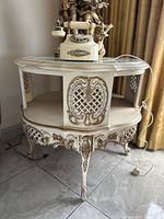 Front view of entire oval side table showing carved floral and lattice details, single lower shelf and three curved legs