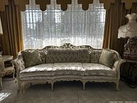 Front view of sofa showing carved wooden frame and floral upholstery