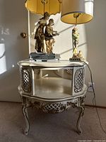 Front view of cream-colored ornate carved wood side table with open shelf, lattice panels, curved cabriole legs