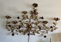 Full frontal view of the gilt metal floral wall sconce mounted on wall.