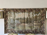 Full view of the large vintage woven tapestry depicting a terrace overlooking Lake Como with floral border.