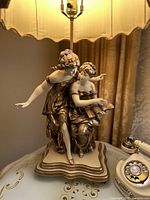 Front and side views of the large figural lamp showing two classical ladies, detailed gold leaf on dresses, and cream sculpted faces.