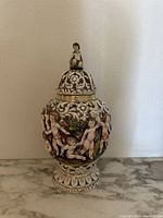 Front view of the Capodimonte porcelain vase showing cherub designs and floral scrolls.