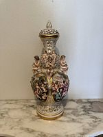 Front view of large vintage Capodimonte Bernini porcelain vase showing cherubs and hand-painted scenes on bulbous body with ornate floral scroll design on neck and base.