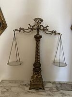 Full frontal view of the entire vintage brass scales of justice with glass trays balanced on chains.