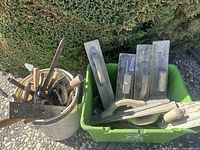 Overview of grout finishing tools including grout floats and hand tools in bucket and bin outdoors