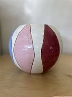 Front angle of rounded vase showing vertical colored panels in light blue, pink, burgundy and white with gold lines