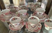 Shelf display showing multiple teacup and saucer sets arranged in rows