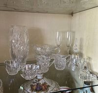 Assorted vintage Marquis by Waterford crystal glassware in display cabinet including vase, glasses, bowls, bell, decanter.