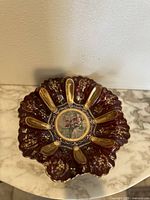Top-down view showing the entire ruby red cut glass bowl with gold gilt and center painted medallion.