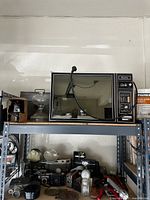 Vintage microwave oven on top shelf with various vintage cameras and accessories below.