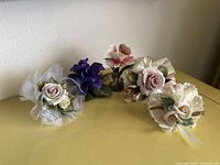 All five delicate porcelain flower pieces shown together on yellow surface