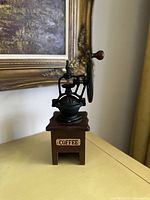 Front angled view showing coffee grinder wooden base with COFFEE label and metal grinding mechanism with handle