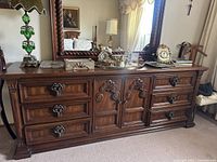 Front view of the vintage Drexel dresser credenza in wood with detailed carving and ornate handles, holding decorative items (not included)