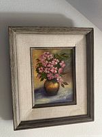 Frontal image of vintage framed still life painting of pink flowers in a vase, showing full artwork and frame.