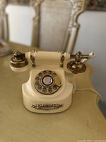 Front view of vintage French rotary home telephone in cream color with brass details.