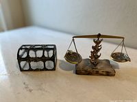 Photo showing the treasure chest and balancing scale side by side on a flat surface, both with clear visible details.