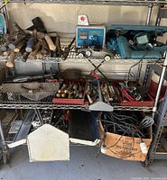 Wide view of metal shelves with vintage hammers, screwdrivers, hand saw, power tools, and other items