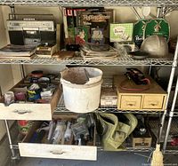 Full view of metal shelving unit holding various vintage items including helmet, magazines, radio, hardware supplies and small drawers