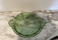 Top-down image showing the entire green depression glass plate with Cherry Blossom pattern and two handles.
