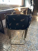 Close-up of folded TV tray with black surface and gold fern leaf design showing the pattern and tray edge shape