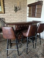 Full view of vintage mid-century style bar and three matching tufted vinyl bar stools set, showing upholstery, button tufting and metal legs.