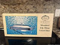 Box showing product image and labeled as Regent Folio Silverplated 2 Qt Oblong Covered Baker.