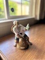 Side view of the vintage Shiwan figurine showing fisherman sitting on basket holding fish.