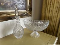 Both Waterford crystal pieces, footed centerpiece bowl and decanter, displayed together on a table.