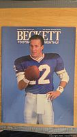 Magazine cover featuring a color photo of an NFL player wearing number 12 football uniform holding a football on the January 1988 issue of Beckett Football Monthly.