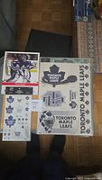 Photo showing two sheets of Toronto Maple Leafs stickers on a floor