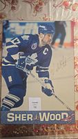Wooden picture of Wendal Clark in Toronto Maple Leafs uniform holding hockey stick, includes printed signature, mounted on wood.