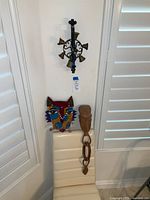 Photo of corner with cat wall clock on wall, vintage wrought iron doorbell mounted above chair and African wooden carved art piece resting on chair.