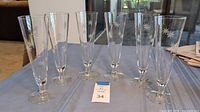 Front view of six clear Gilley beer flutes arranged in a line on a table with white etched starburst designs on each glass.