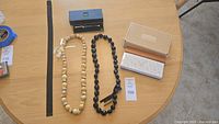 Full lot showing metal elastic belt, two necklaces, boxed new Cross pen, and Schleeh post-it/note pad holder on table with lot tag 109 visible