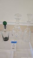 Lot of three vintage decanter bottles displayed on white cloth.