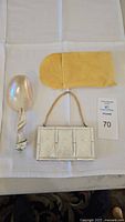 Full lot with mother of pearl spoon, compact makeup kit, and yellow protective pouch laid out on white cloth