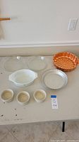 View of all items on table: 3 Pyrex dishes, 2 cake pans, 3 small bowls.