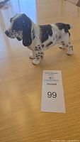 Front-side view of the Cocker Spaniel figurine on wooden table with auction tag visible