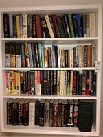 Full view of four shelves tightly packed with assorted books of various sizes and colors.