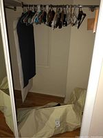 Image of multiple wooden, plastic, and metal clothes hangers on closet rod, showing colors, types, and wear.