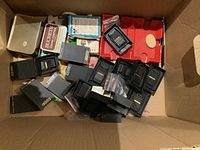 Cardboard box containing multiple Zippo branded cases including pocket cutting utensils and tape measures, poker accessories, and cribbage board.
